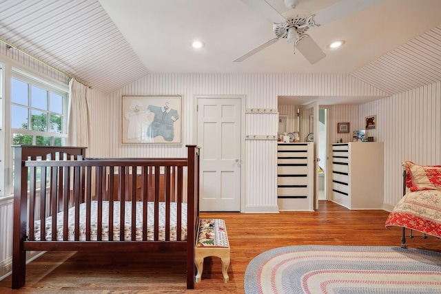 bedroom with wallpapered walls, vaulted ceiling, recessed lighting, and wood finished floors