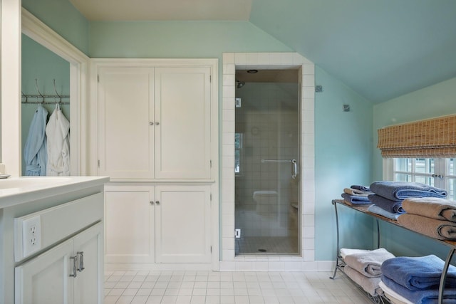 bathroom featuring tile patterned floors, lofted ceiling, vanity, and a shower stall