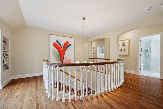 corridor featuring lofted ceiling, wood finished floors, and baseboards