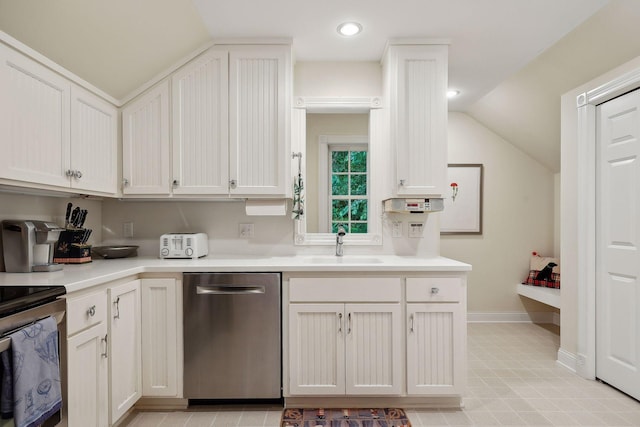 kitchen with vaulted ceiling, stainless steel appliances, light countertops, and a sink