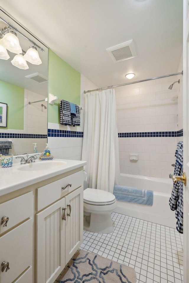 bathroom featuring visible vents, shower / bath combination with curtain, tile patterned floors, toilet, and tile walls