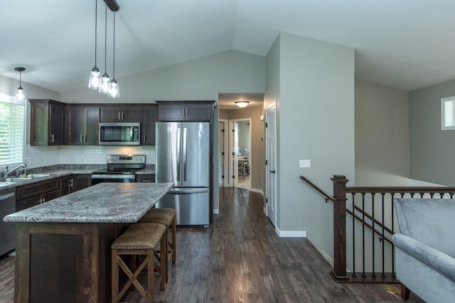 kitchen with sink, appliances with stainless steel finishes, dark hardwood / wood-style floors, a center island, and vaulted ceiling