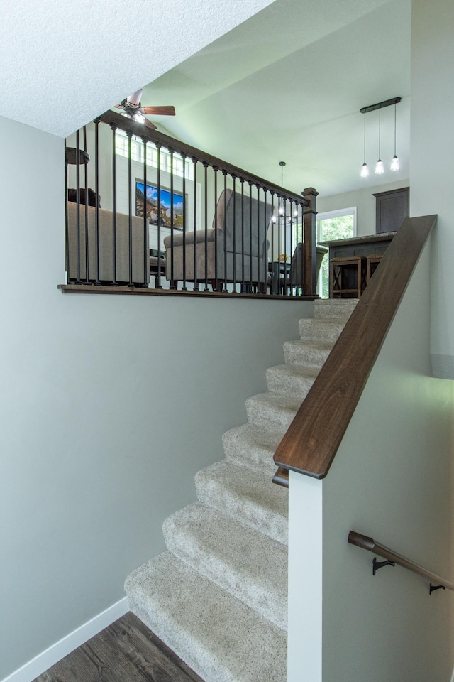 stairs featuring baseboards, wood finished floors, and ceiling fan