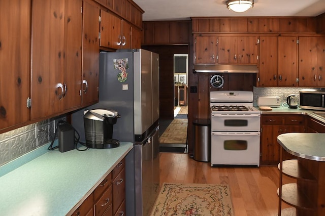 kitchen with stainless steel appliances, light wood-type flooring, and tasteful backsplash