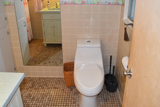 bathroom with tile walls, toilet, vanity, and tile patterned floors