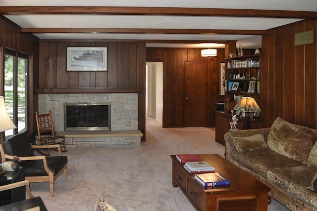 carpeted living room with wood walls, a stone fireplace, and beam ceiling