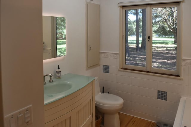 bathroom with tile walls, hardwood / wood-style floors, toilet, and vanity