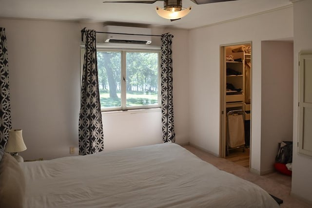 bedroom featuring a walk in closet, carpet, a closet, an AC wall unit, and ceiling fan