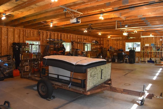 garage with a garage door opener, ceiling fan, and wooden walls