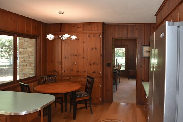 dining room featuring light wood-style floors, a chandelier, and wood walls