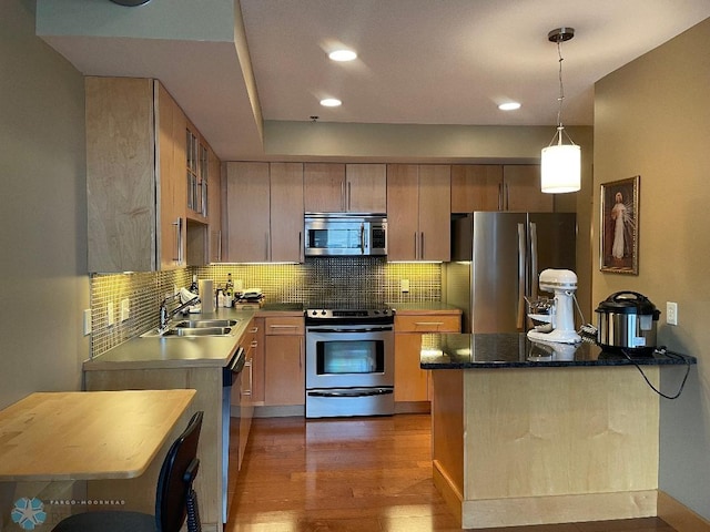 kitchen with pendant lighting, dark wood-type flooring, sink, backsplash, and appliances with stainless steel finishes