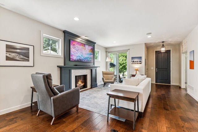 living room featuring dark wood-type flooring, a fireplace, visible vents, and baseboards