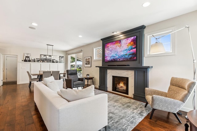 living area with baseboards, dark wood finished floors, a high end fireplace, and recessed lighting