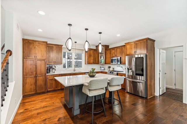 kitchen with light countertops, appliances with stainless steel finishes, a sink, and dark wood finished floors