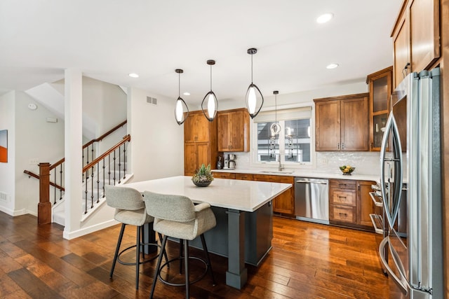 kitchen featuring dark hardwood / wood-style floors, a kitchen breakfast bar, hanging light fixtures, stainless steel appliances, and a center island