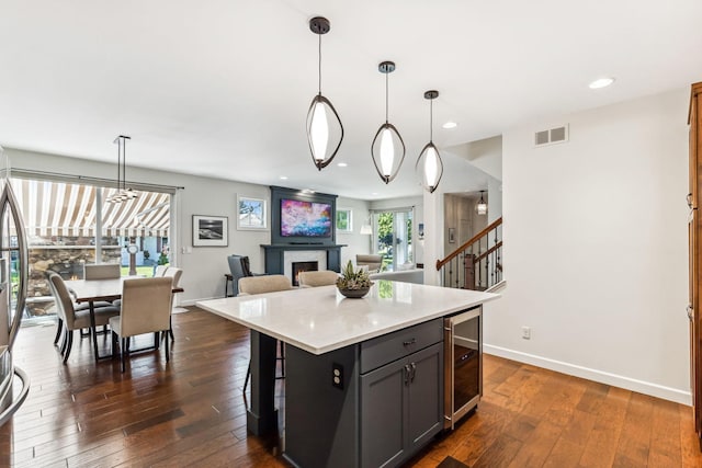 kitchen with dark wood-type flooring, plenty of natural light, a center island, and pendant lighting