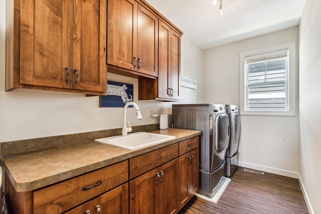 clothes washing area featuring separate washer and dryer, a sink, baseboards, cabinet space, and dark wood-style floors