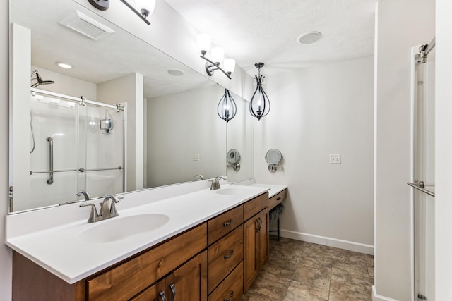 full bath with double vanity, a sink, a shower with door, and baseboards