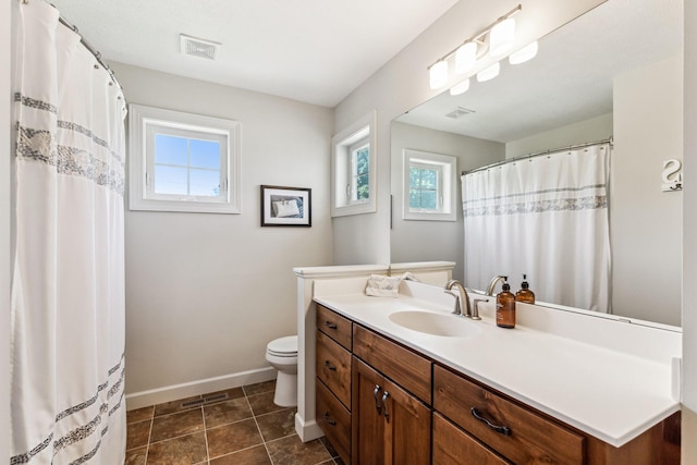 bathroom with vanity, toilet, a healthy amount of sunlight, and tile patterned floors