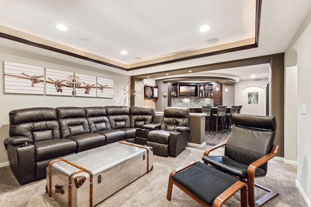 home theater featuring carpet flooring, bar area, a tray ceiling, and crown molding