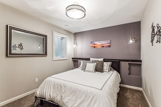 bedroom featuring a textured ceiling and dark colored carpet