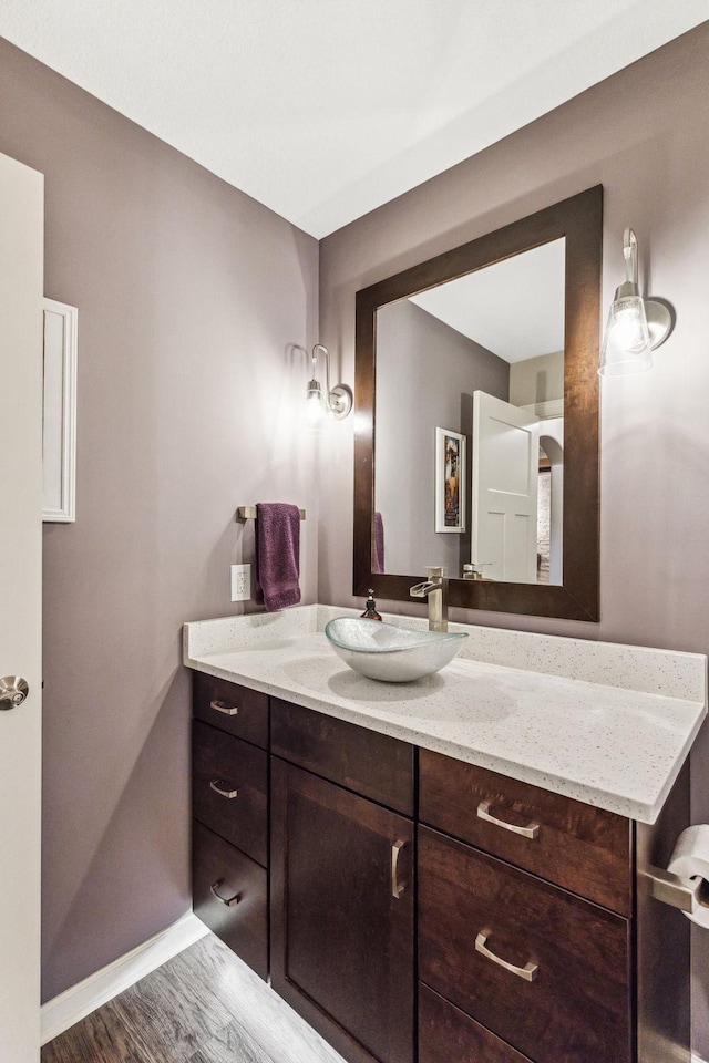 bathroom with wood finished floors, vanity, and baseboards