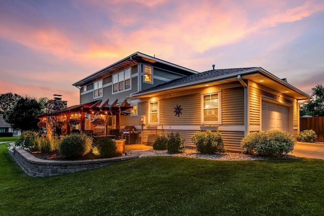 back house at dusk featuring a lawn and a garage