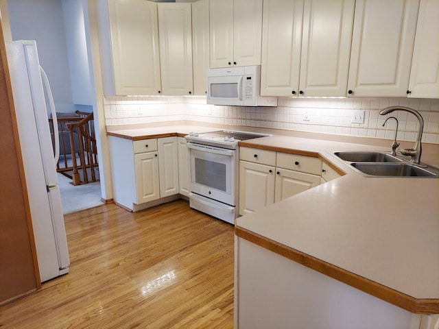 kitchen featuring white appliances, sink, light hardwood / wood-style flooring, decorative backsplash, and white cabinetry