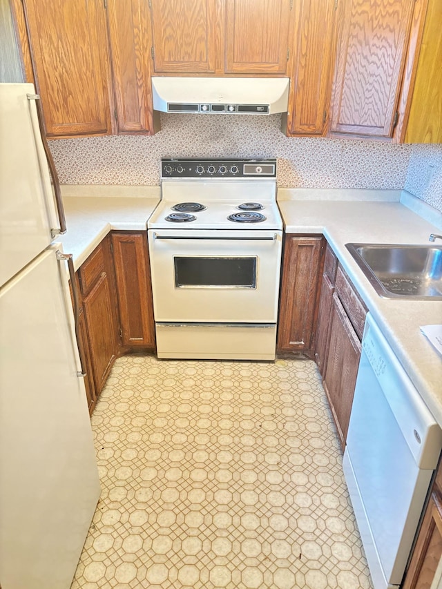 kitchen featuring a sink, ventilation hood, white appliances, light countertops, and light floors