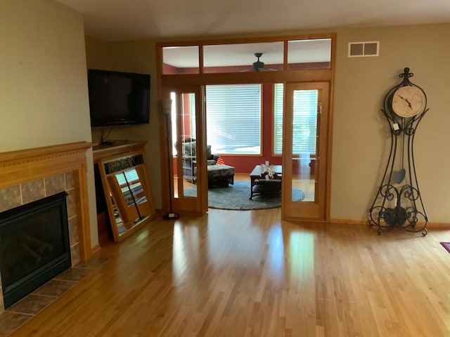 living room with a tile fireplace, ceiling fan, and hardwood / wood-style flooring