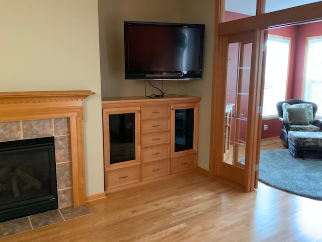 living room featuring light wood-type flooring and a tile fireplace