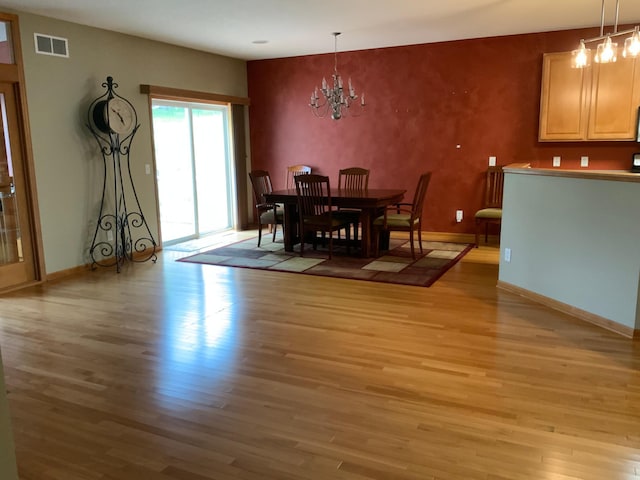 dining space featuring light hardwood / wood-style floors and a chandelier