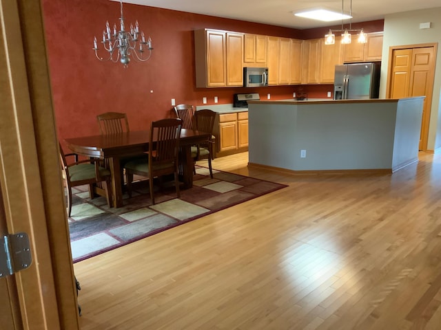 kitchen featuring light wood-type flooring, a chandelier, stainless steel appliances, and decorative light fixtures