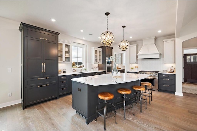 kitchen with white cabinetry, a kitchen island, custom exhaust hood, a kitchen breakfast bar, and high end stainless steel range