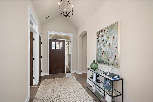 entryway with an inviting chandelier, high vaulted ceiling, and dark wood-type flooring