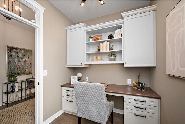 office with built in desk and dark hardwood / wood-style flooring