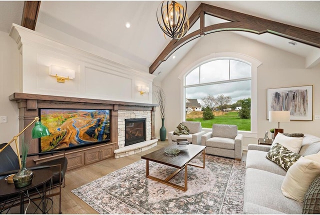 living room with light wood-type flooring, a chandelier, beam ceiling, a fireplace, and high vaulted ceiling