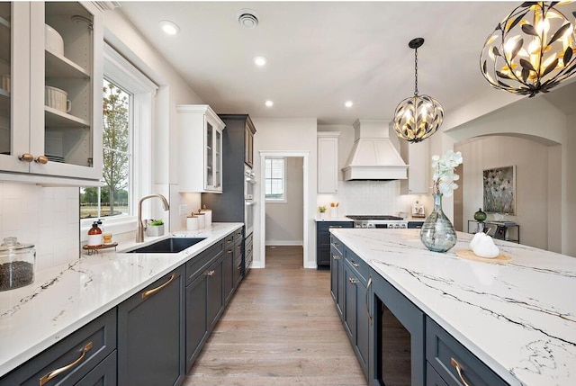 kitchen featuring white cabinets, custom exhaust hood, and a healthy amount of sunlight