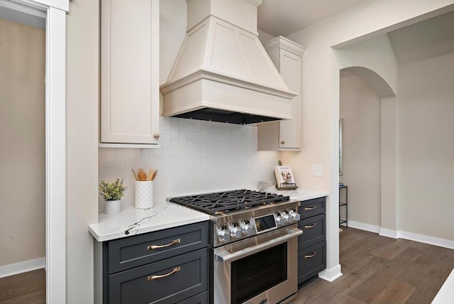 kitchen with high end stainless steel range oven, dark wood-type flooring, white cabinetry, custom exhaust hood, and backsplash