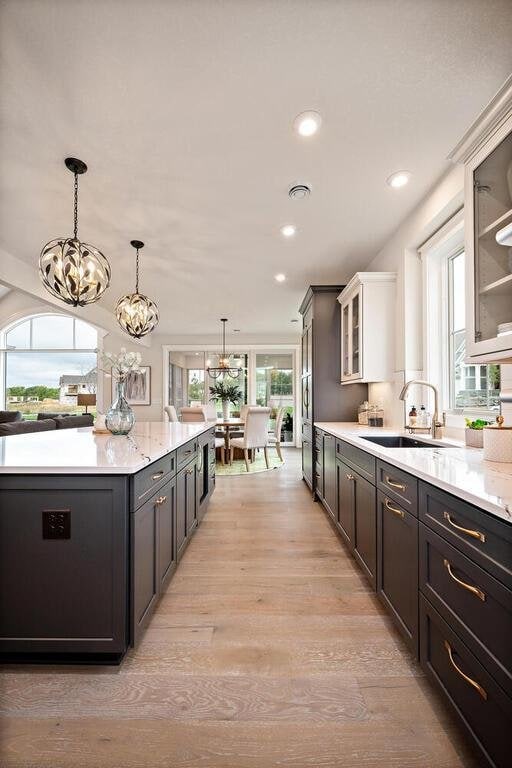 kitchen featuring white cabinets, an inviting chandelier, light hardwood / wood-style flooring, decorative light fixtures, and sink