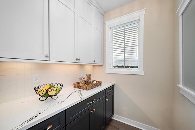 interior space with tasteful backsplash, light stone countertops, and white cabinets