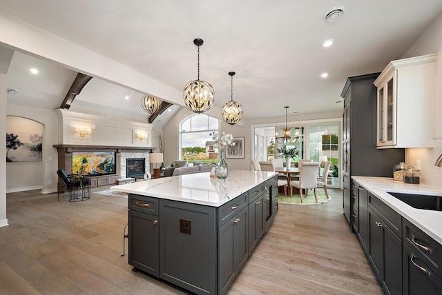 kitchen with light hardwood / wood-style flooring, white cabinets, plenty of natural light, and a fireplace