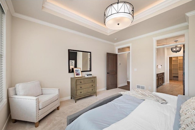 carpeted bedroom with ornamental molding, ensuite bath, and a raised ceiling