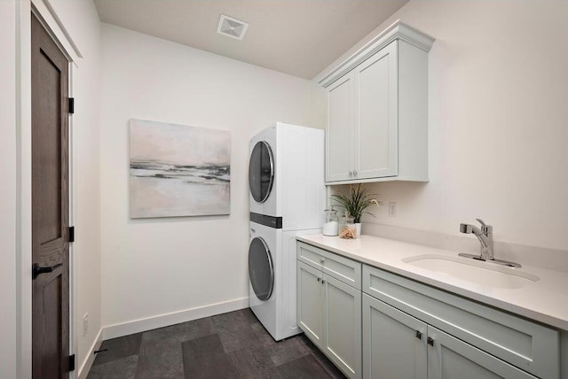 washroom featuring cabinets, stacked washer / drying machine, and sink