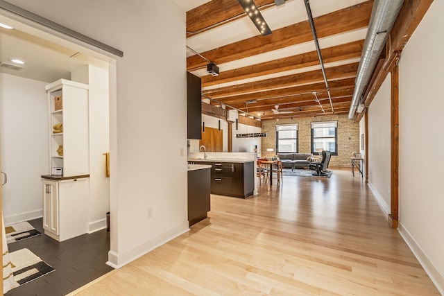 interior space with light hardwood / wood-style flooring, brick wall, and sink