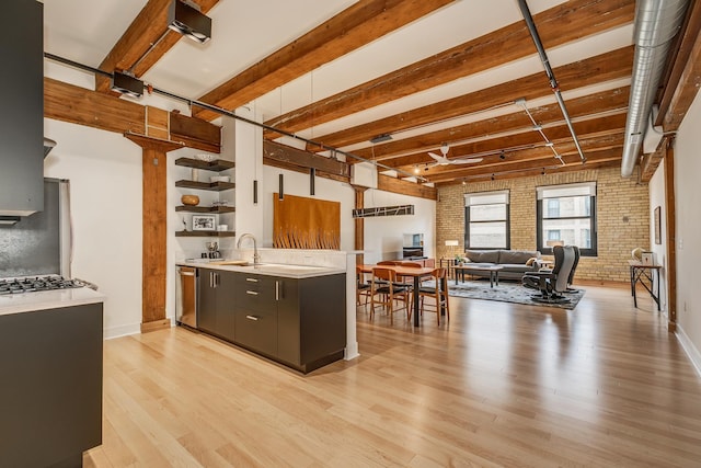 kitchen featuring light wood-type flooring, stainless steel appliances, sink, and brick wall