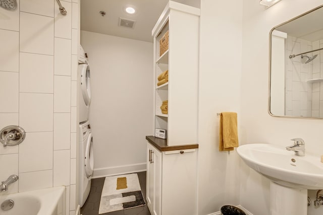 bathroom featuring tiled shower / bath combo, stacked washing maching and dryer, and tile patterned floors