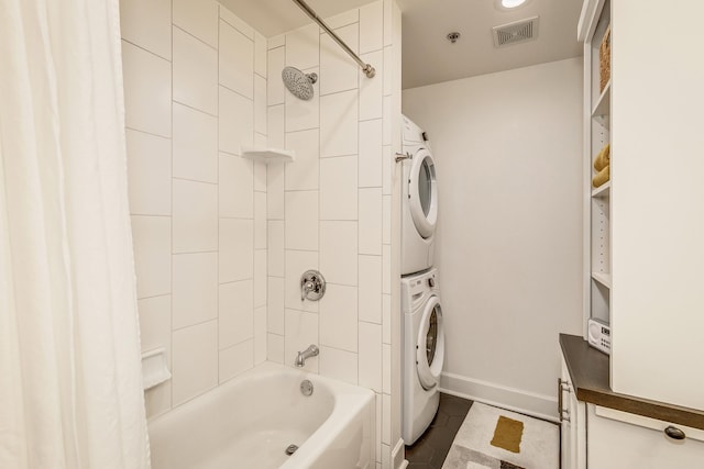 bathroom featuring shower / bath combo with shower curtain, stacked washer and dryer, and tile patterned floors