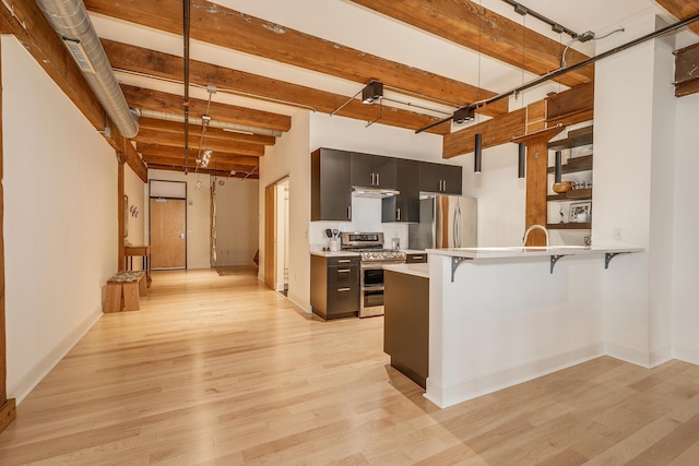 kitchen featuring light wood-type flooring, kitchen peninsula, stainless steel appliances, and a breakfast bar