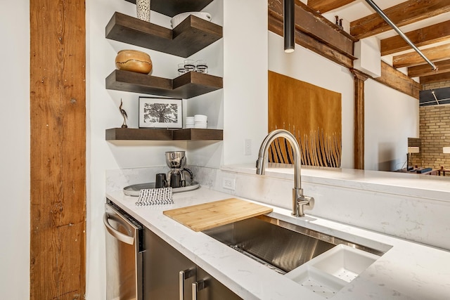 kitchen featuring light stone countertops, dishwasher, sink, and brick wall